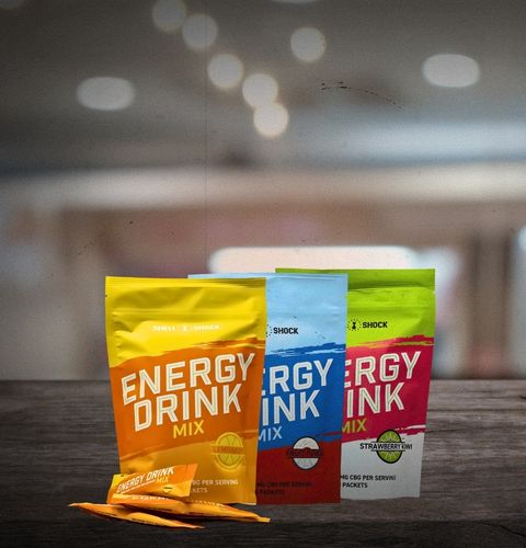 Three energy drink mix packets on a wooden surface with a blurred background